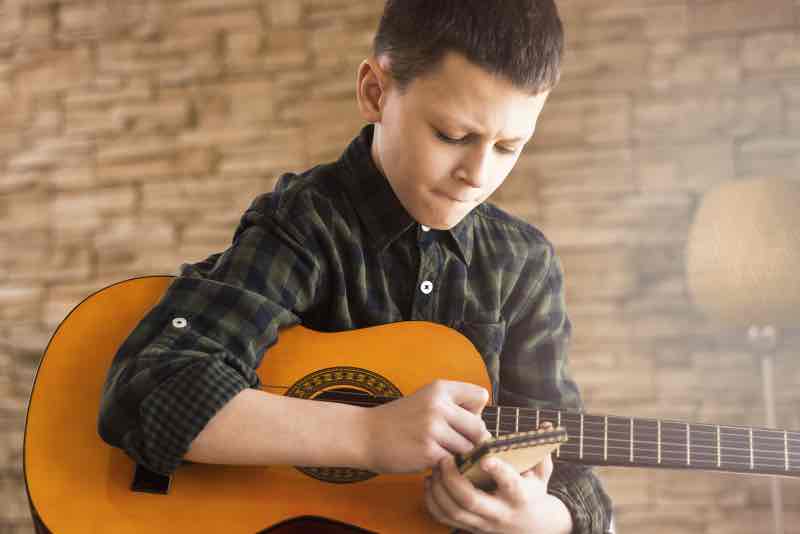 Boy with Acoustic Guitar Writing Songs in Living Room