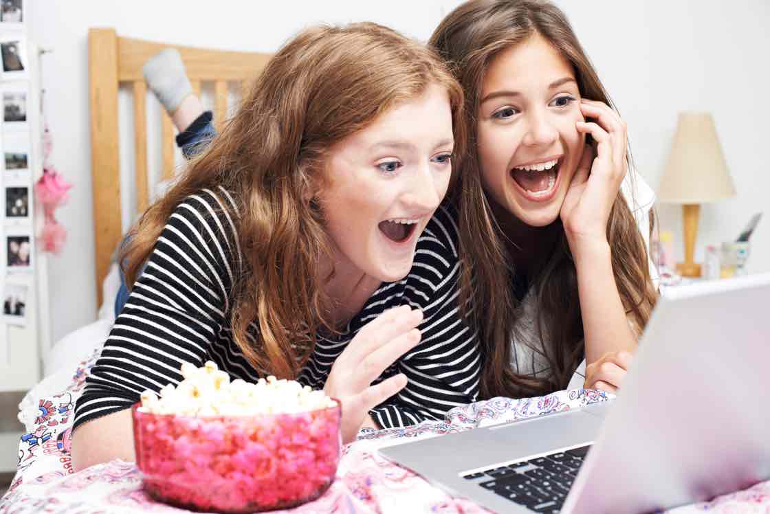 Two Teenage Girls Watching Movie On Laptop In Bedroom